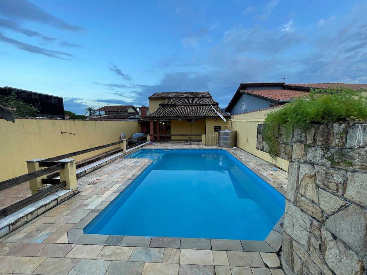 Piscina da casa, com piso de pedra em volta